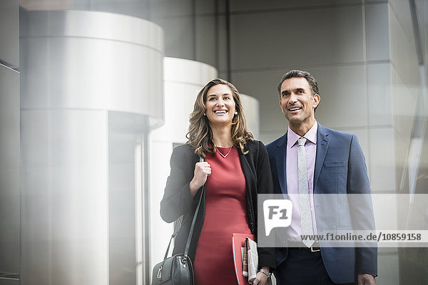 Smiling corporate businessman and businesswoman outside building