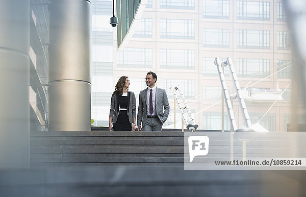 Corporate businessman and businesswoman descending stairs outdoors