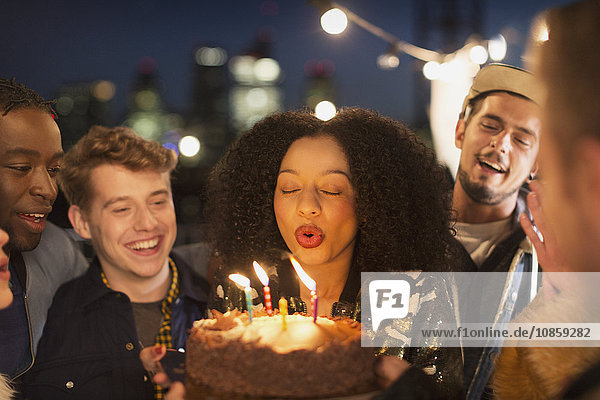 Freunde feuern junge Frau an  die Geburtstagskerzen ausbläst.