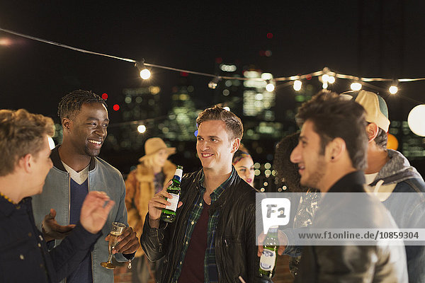 Young men drinking beer and talking at rooftop party