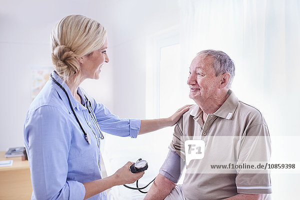 Der Arzt überprüft den Blutdruck des älteren Mannes bei der Untersuchung.