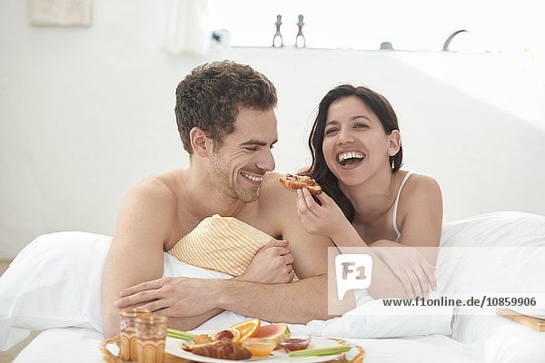 Young couple having breakfast in bed