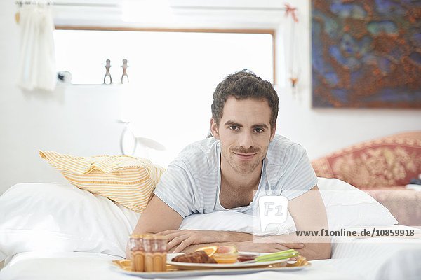 Junger Mann frühstückt im Bett
