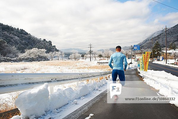 Rückansicht eines reifen männlichen Läufers  der im Winter auf der Straße läuft  Kawaguchiko-See  Berg Fuji  Japan