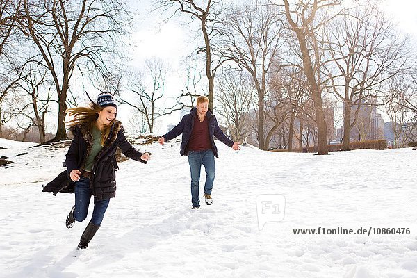 Young couple running in snowy Central Park  New York  USA