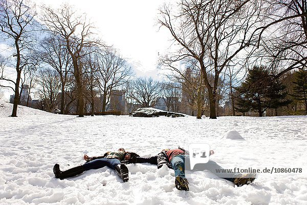 Young couple lying down in snowy Central Park  New York  USA