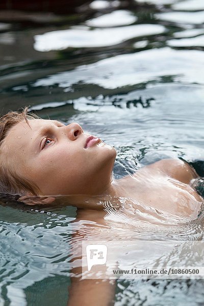 Boy floating in swimming pool gazing upward