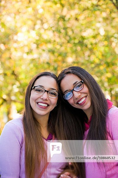 Twin sisters smiling wide in park