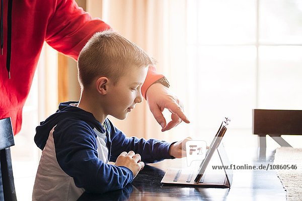 Vater und Sohn benutzen drahtloses digitales Tablet zu Hause
