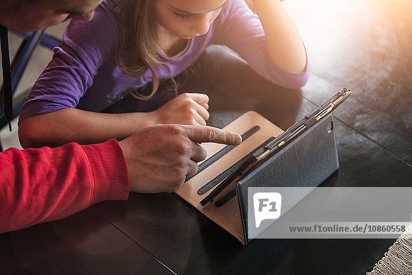 Vater und Tochter benutzen drahtloses digitales Tablet zu Hause