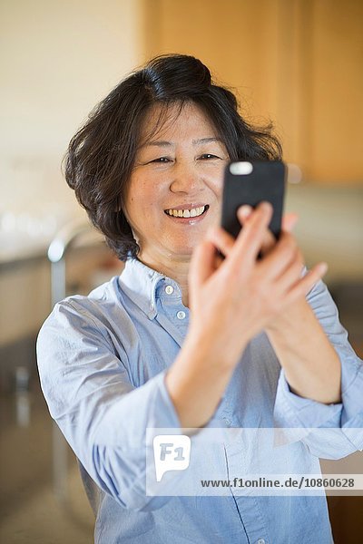 Mature woman taking selfie indoors