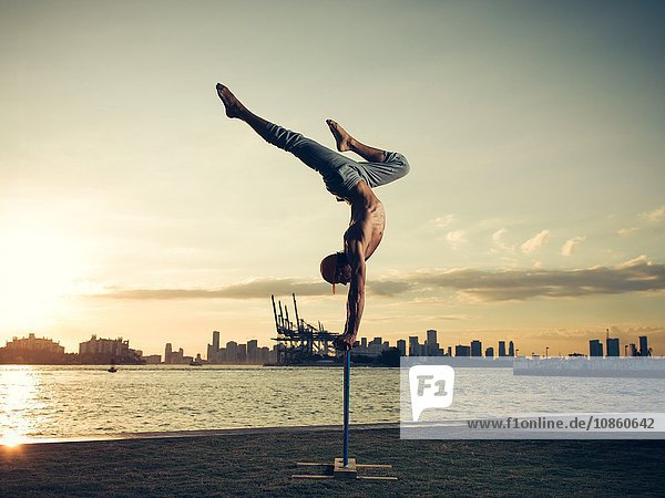 Mature man doing handstand on pole South Pointe Park South Beach Miami Florida USA