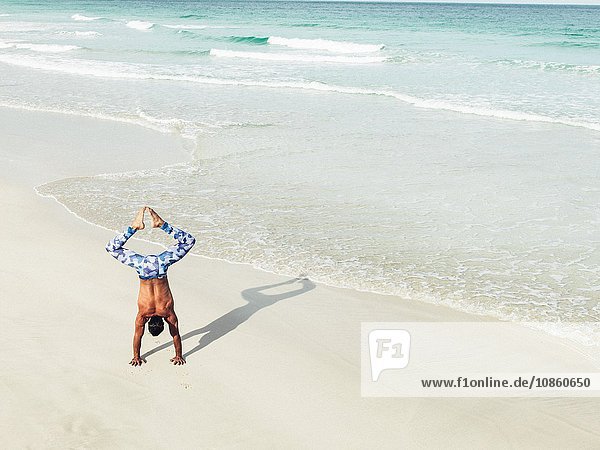 Mature man doing handstand on beach South Pointe Park South Beach Miami Florida USA