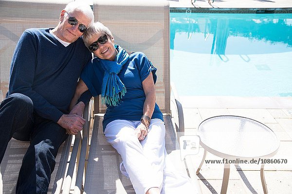 Älteres Ehepaar entspannt sich auf Liegestühlen am Pool