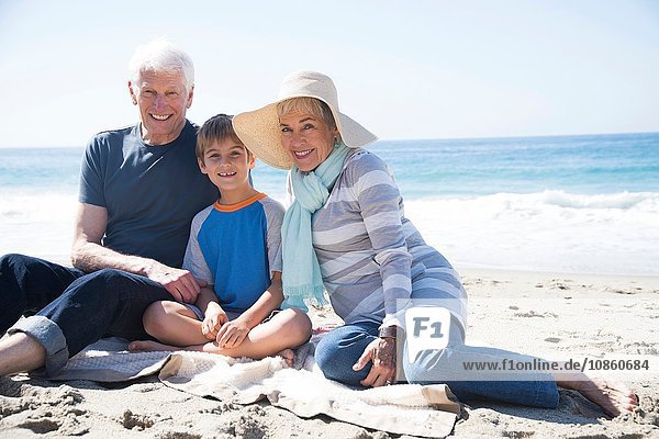 Porträt der Großeltern und des Enkels  am Strand sitzend  lächelnd