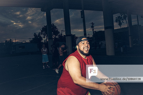 Mid adult man wearing vest playing basketball open mouthed smiling