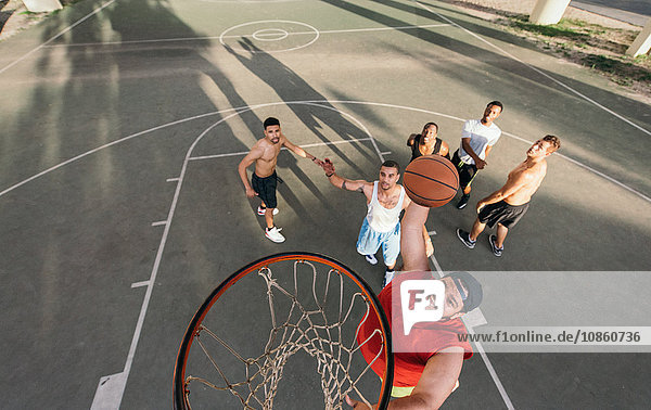 High angle view of young man on basketball court doing slam dunk