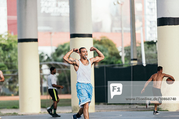 Tattooed man flexing muscles sticking out tongue looking away smiling