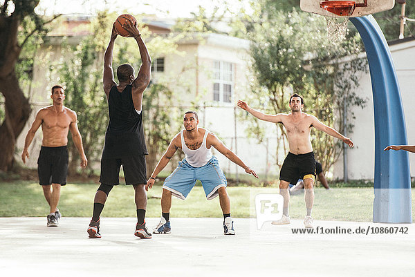 Men on basketball court playing basketball defending hoop