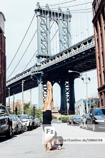 Young man doing yoga handstand in front of Manhattan Bridge  New York  USA