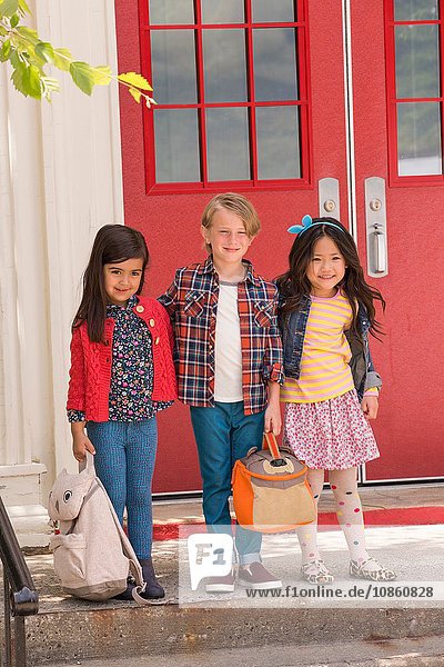 Portrait of elementary schoolboy and girls standing at elementary school doorway