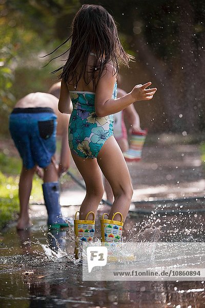 Kinder spielen mit Wasserschlauch auf dem Bürgersteig
