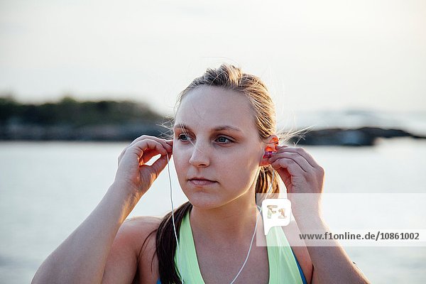 Woman inserting earbuds looking away
