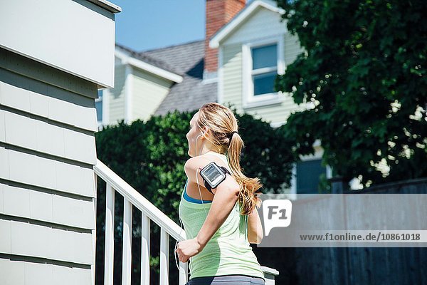 Rear view of woman wearing activity tracker running up stairs