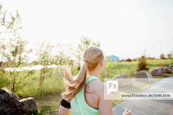 Head and shoulders of woman wearing activity tracker jogging on path