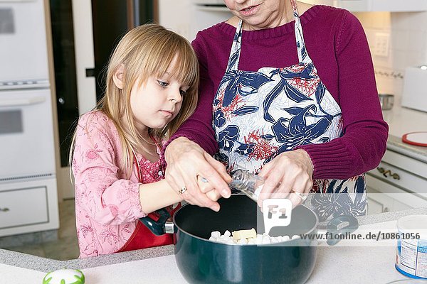 Mädchen und Großmutter messen Salz für Kasserolle