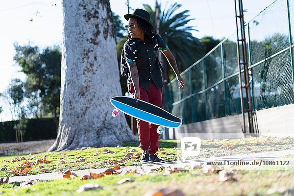 Frau hält Skateboard im Park