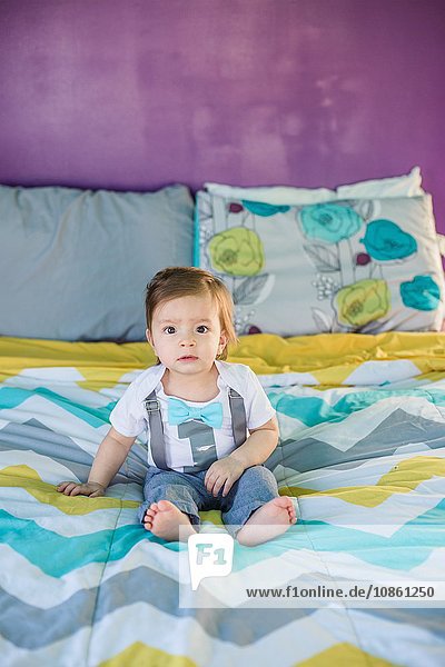 Portrait of baby boy sitting on bed