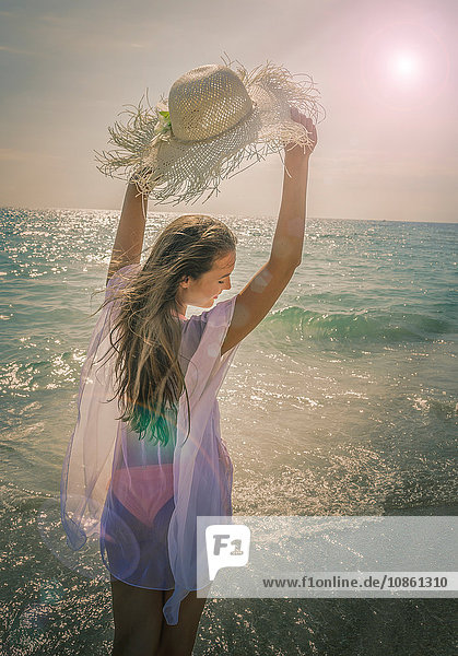 Hübsche junge Frau hält Sonnenhut am Strand von Miami  Florida  USA