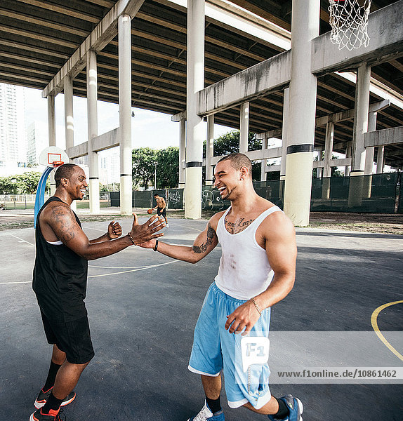 Men on basketball court shaking hand smiling