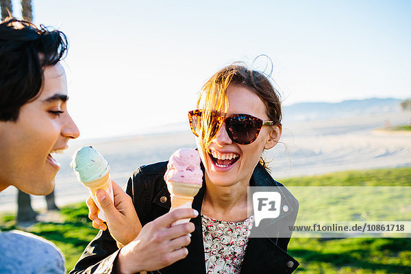 Junges Paar  das sich die Arme verbindet und Eiswaffeln isst  Venice Beach  Kalifornien  USA