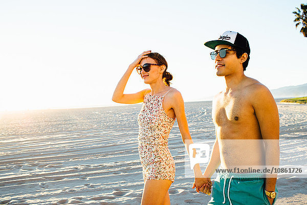 Young couple wearing swimming costume and shorts strolling on beach  Venice Beach  California  USA