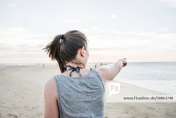 Young woman pointing toward horizon from beach  Tamarindo  Guancaste  Costa Rica