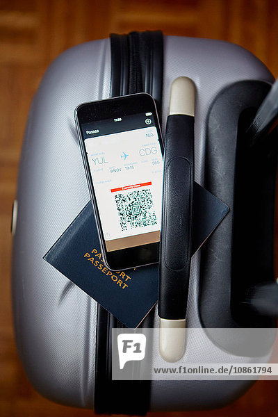 Gepackter Koffer mit Reisepass und Smartphone im Gleichgewicht  Draufsicht