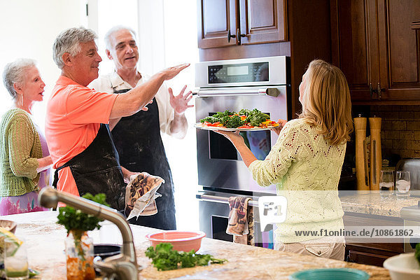 Gruppe von Senioren,  die in der Küche eine Mahlzeit zubereiten