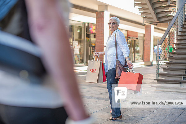 Mature woman shopper waiting for friend in shopping mall