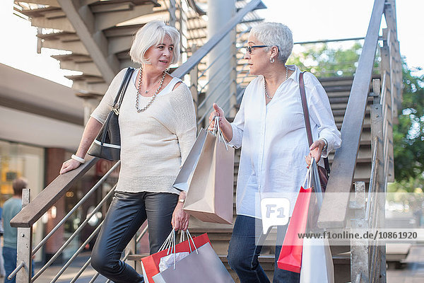 Mature women shoppers moving down shopping mall stairway