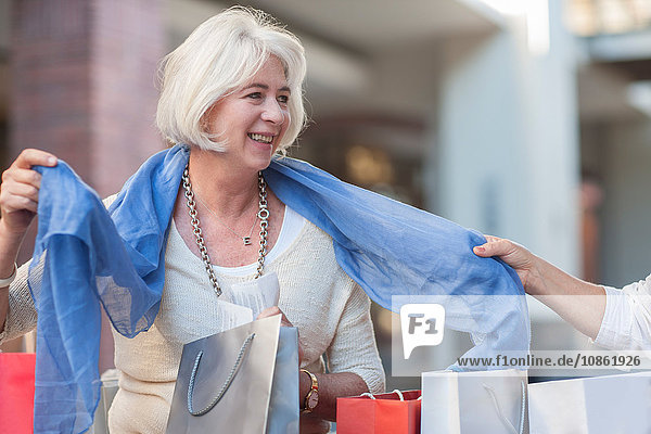 Reife Frau probiert neuen Schal für Freundin im Einkaufszentrum an