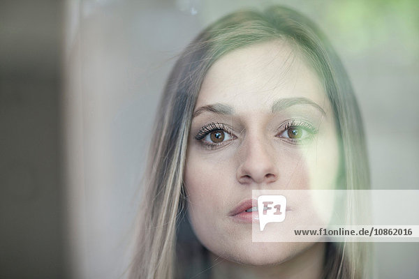 Young woman looking through glass  close-up