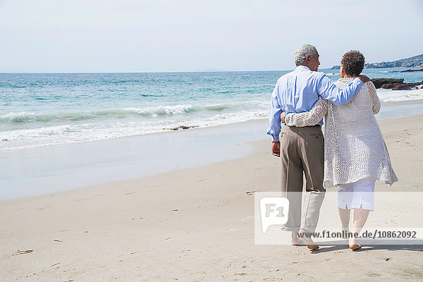 Senior couple waking on beach  rear view