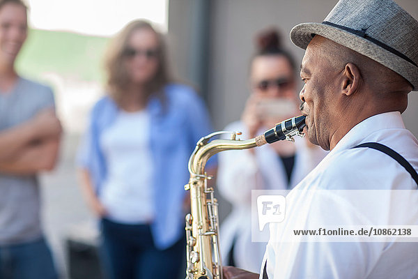 Straßenmusikant  spielt Saxophon  unterhält Fußgänger
