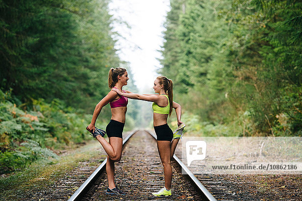 Young woman and teenage girl exercising on rural train track
