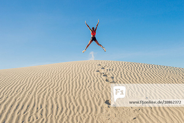Läufer springt mit ausgestreckten Armen und Beinen in der Wüste auf  Death Valley  Kalifornien  USA