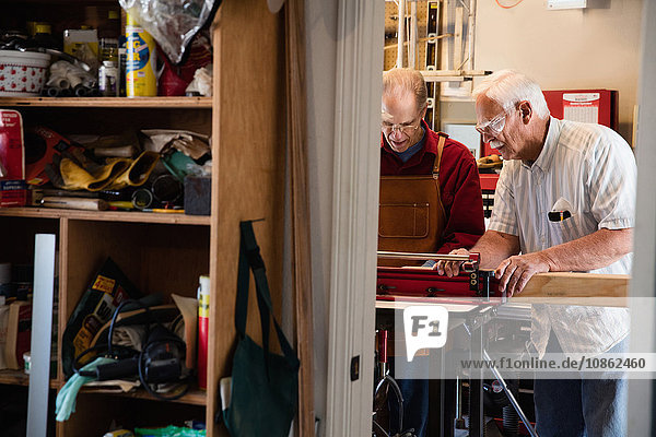Senior men placing woodblock on carpentry equipment workshop
