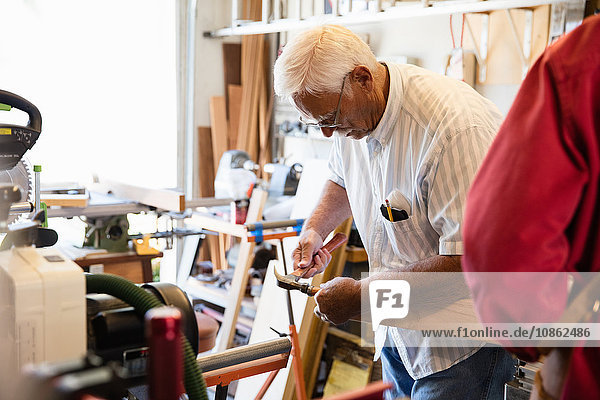 Senior man hammering woodblock in carpentry workshop