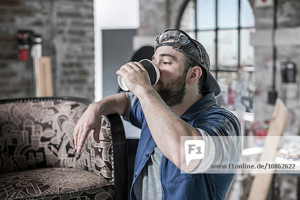 Worker in antique restoration workshop drinking takeaway coffee